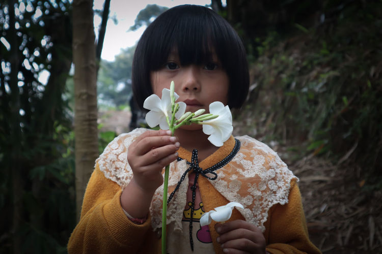 Little girl, honey skinned girl, big eyes, beautiful frangipani flowers