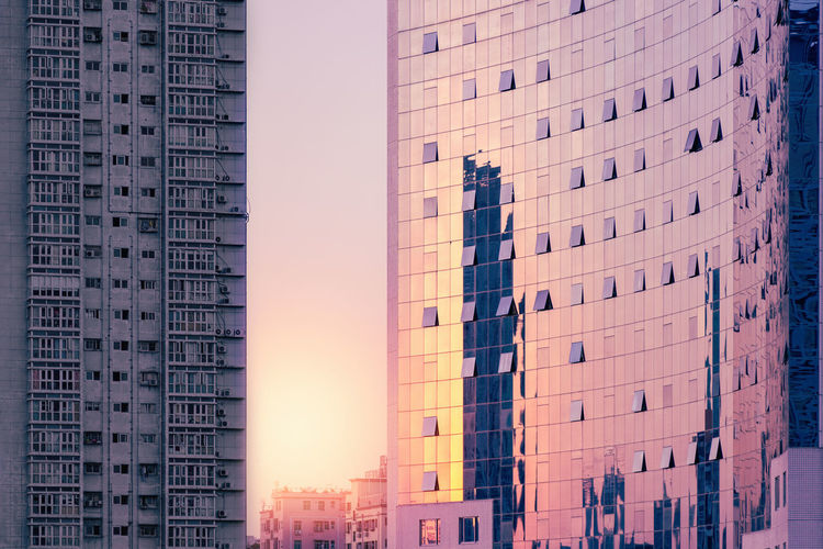 Luxury corporate building at sunset against the background of a gray shabby residential building. 