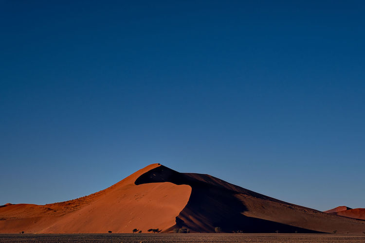 Scenic view of desert against clear blue sky