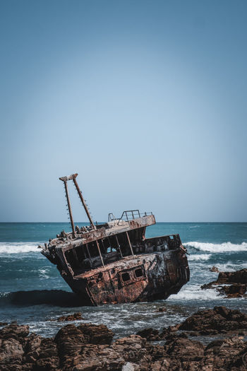 Abandoned ship on beach against clear sky
