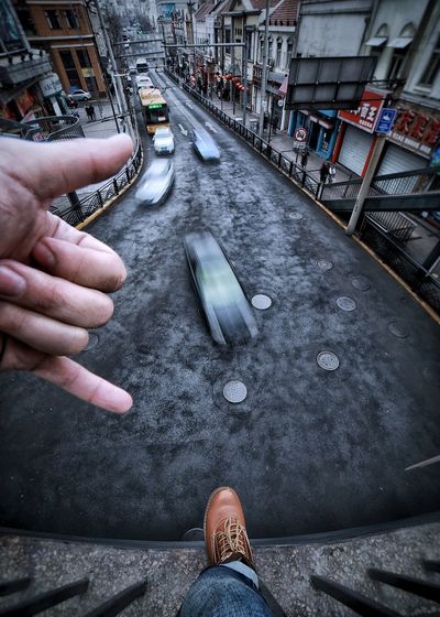 Cropped image of man gesturing shaka sign over road in city