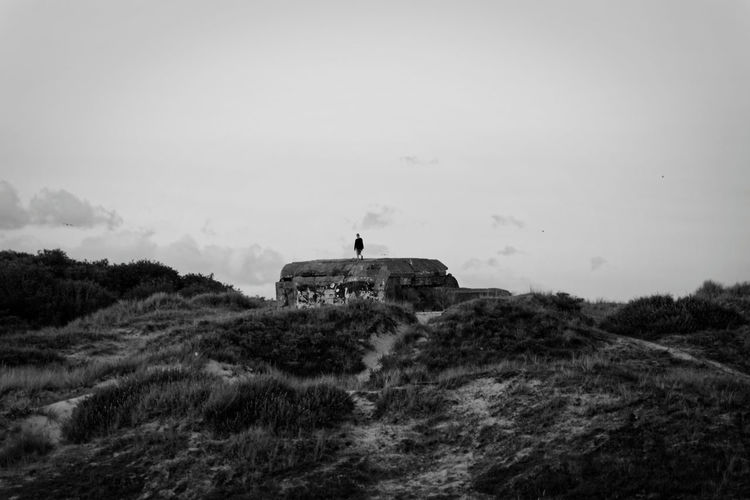 Person standing on rock against sky