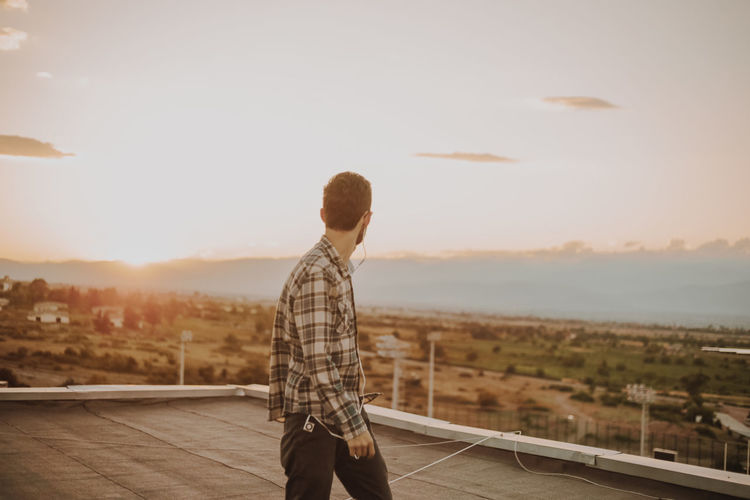 Man standing on terrace against sky during sunset