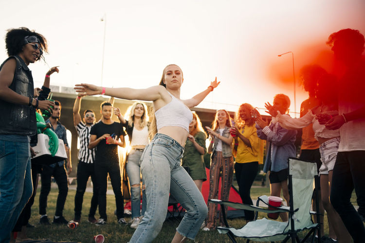 Young woman dancing while friends enjoying in musical event during summer