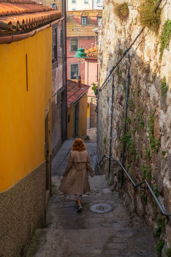 Rear view of woman walking on street amidst buildings