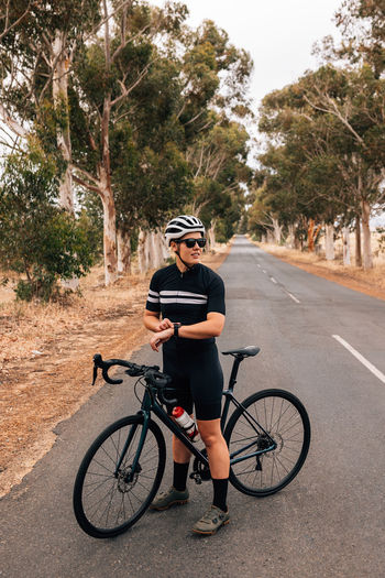 Woman standing with bicycle on road