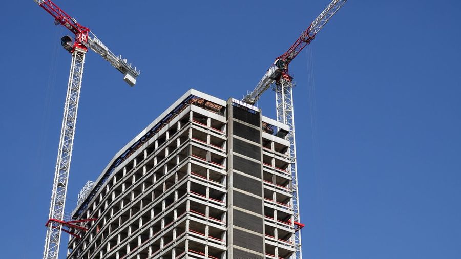Low angle view of crane and building against clear sky