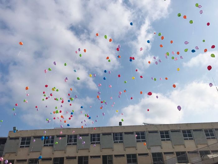 Low angle view of multi colored balloons flying in sky