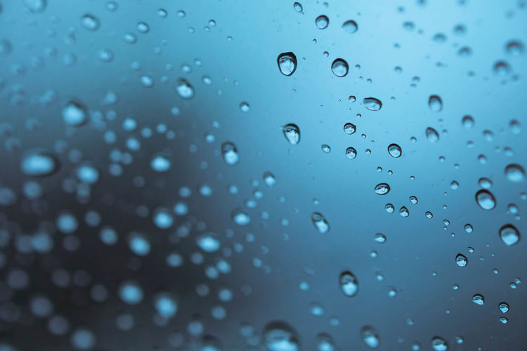 Rain drops on a window, drops of rain on blue glass background