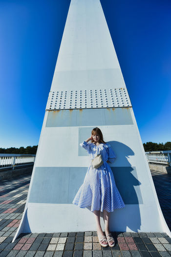 Young woman standing against blue sky