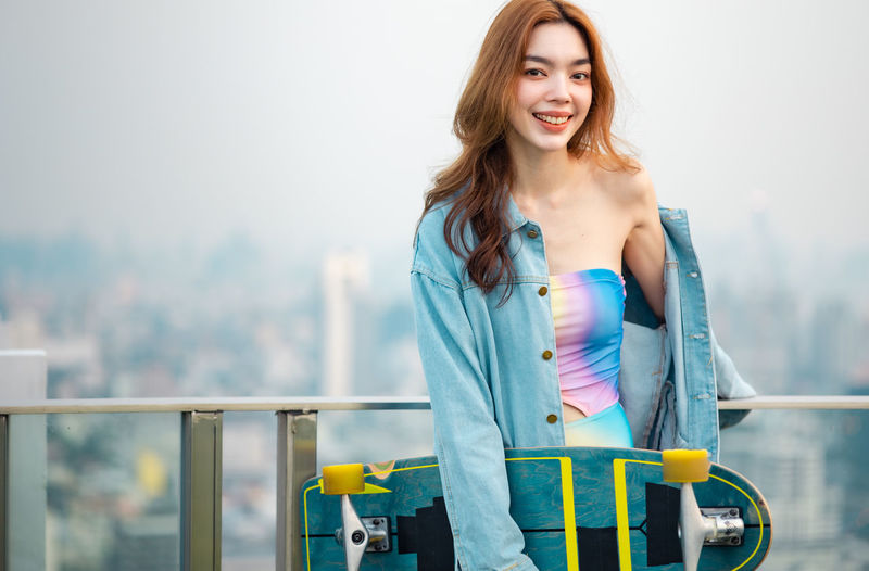 Portrait of smiling young woman standing against railing