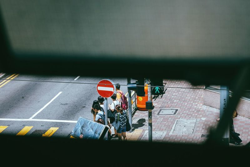 People standing on sidewalk seen through railing