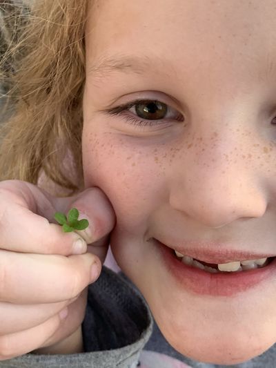 Close-up portrait of smiling girl holding small plant