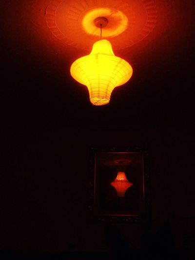 Low angle view of lit lamp hanging in dark room