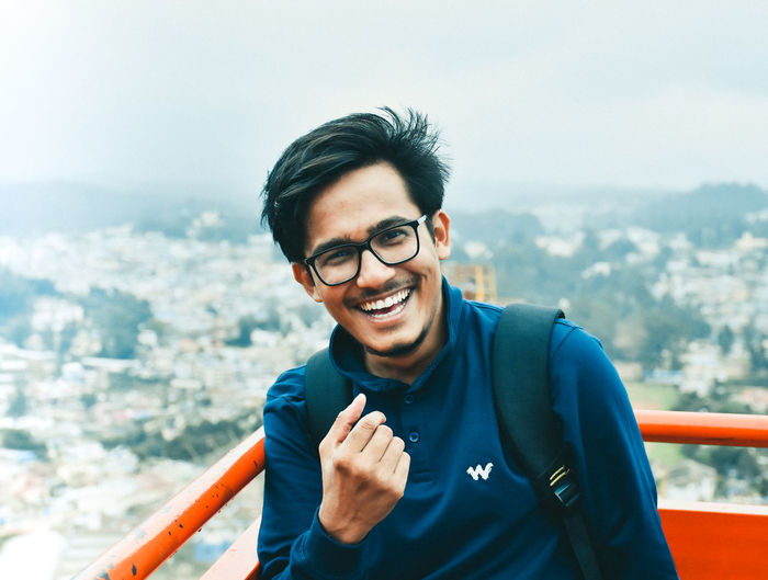 Portrait of smiling young man standing against cityscape