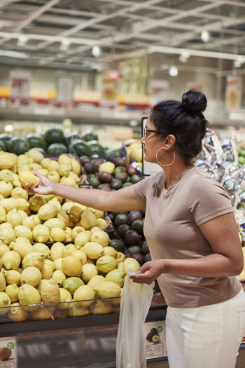 Woman choosing lemon in supermarket