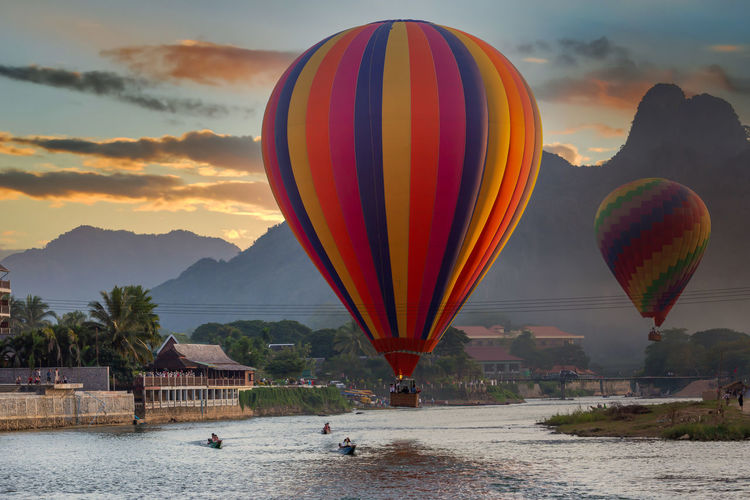 Hot air balloons flying over river against sky