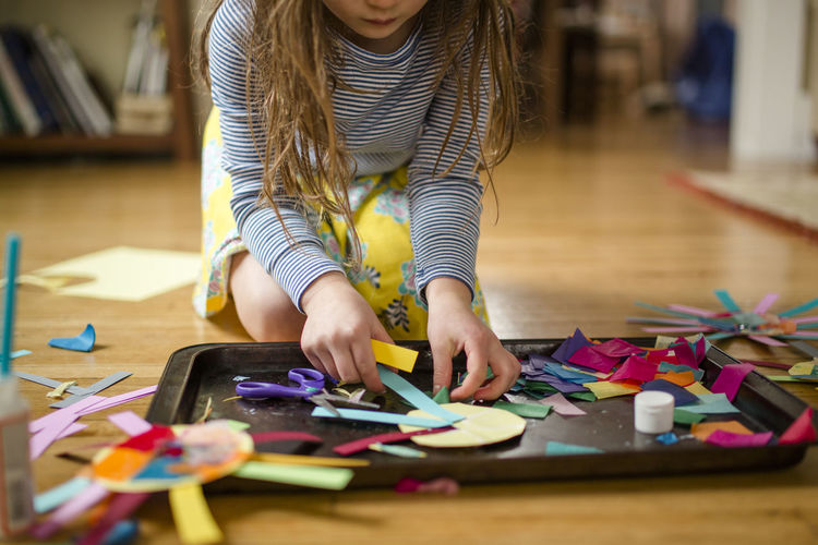 Close up view of a child making paper craft on living room floor
