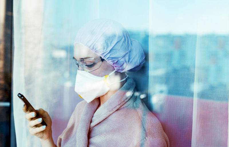 Close-up of doctor using smart phone seen through window