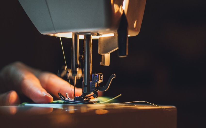 Close-up of hand using sewing machine