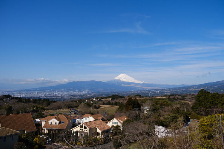 Scenic view of houses and mountains against blue sky