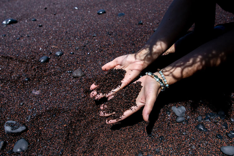 High angle view of woman hands on sand at beach
