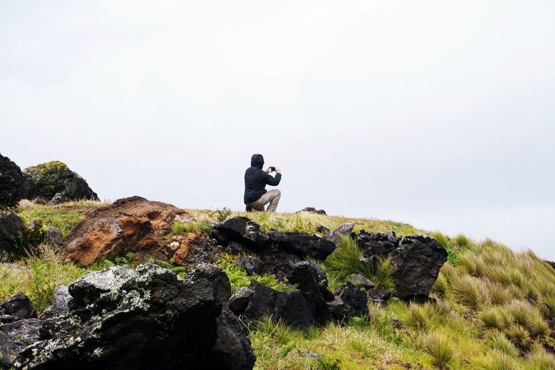 Rear view of man photographing with mobile phone