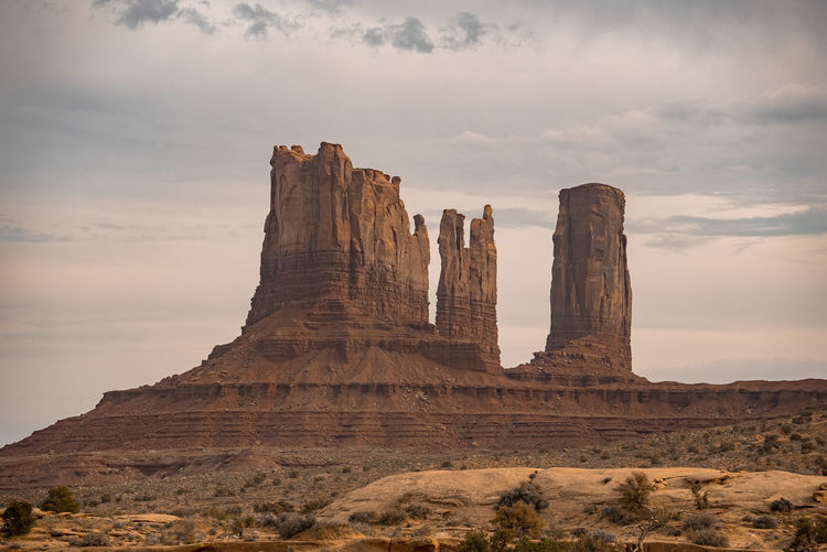 View of rock formations at monument valley with cloudy sky in background