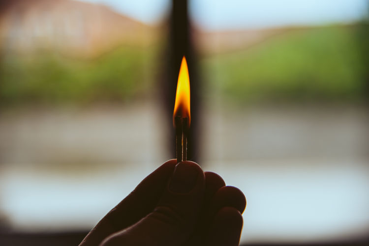 Close-up of hand holding lit candles