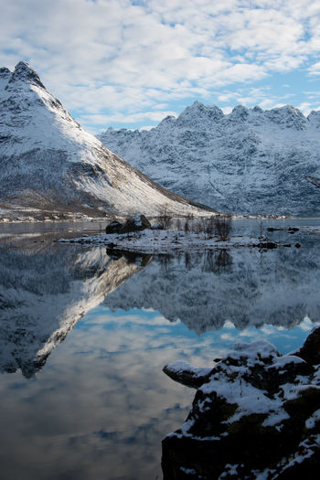 Scenic view of lake by snowcapped mountains against sky