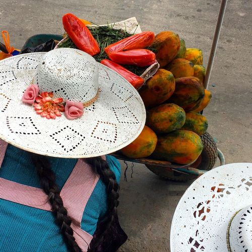 Rear view of woman selling papayas on street in city