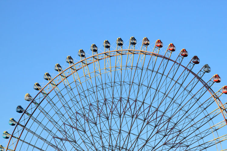 High section of cropped ferris wheel against clear blue sky