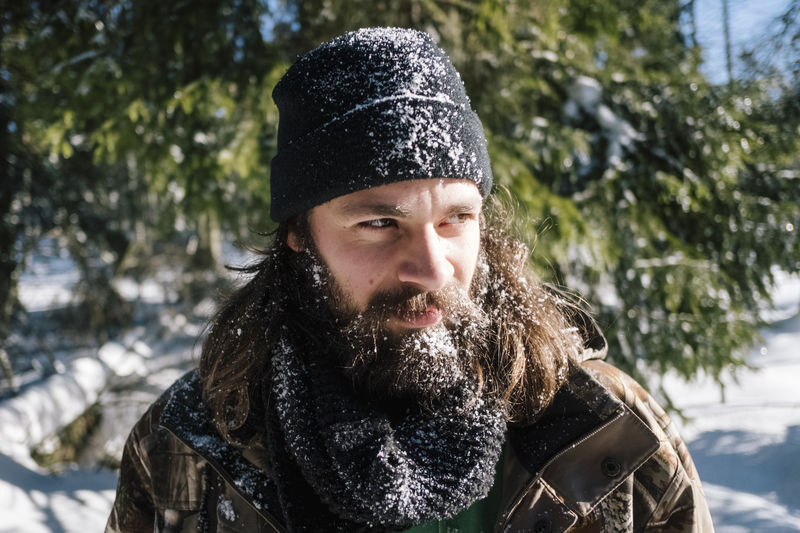 Bearded young man wearing warm clothing while looking away during winter