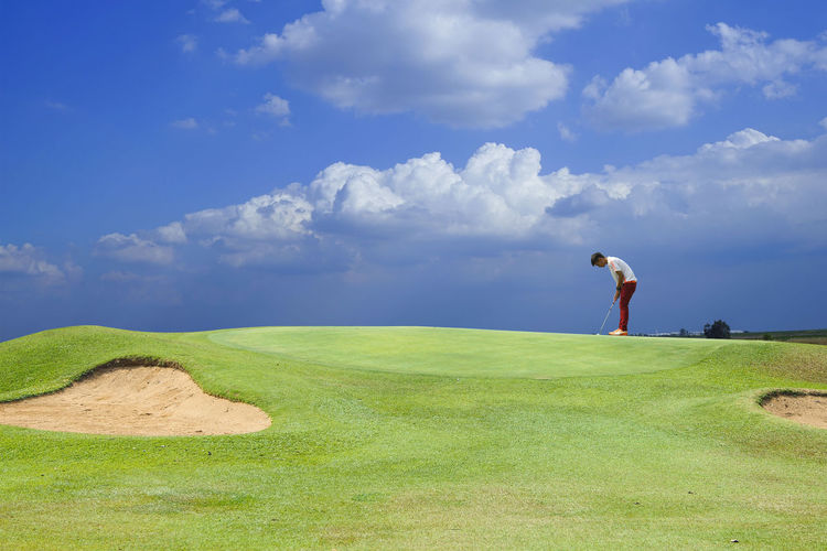 Man standing on golf course against sky