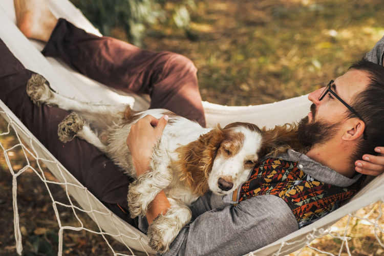 Person sleeping with his dog in a hammock in beautiful summer scene