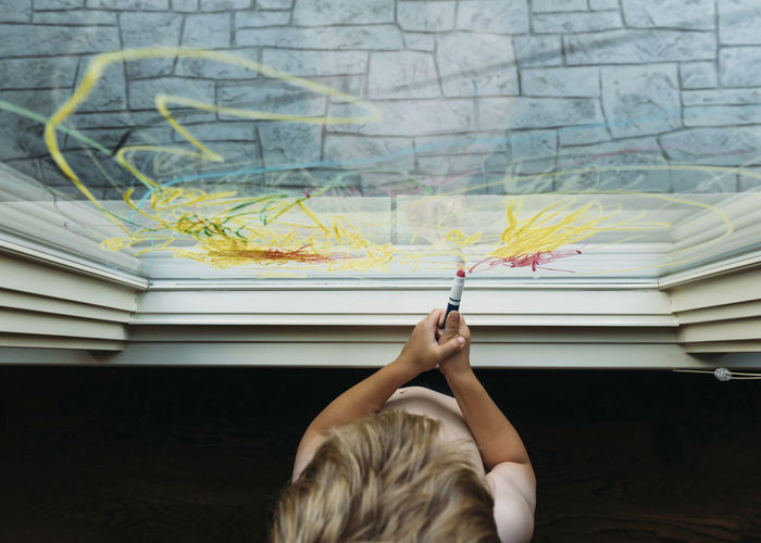 Boy drawing with crayon on window at home