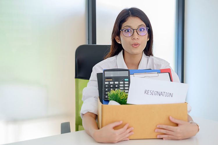 Portrait of businesswoman holding cardboard box in office during resignation