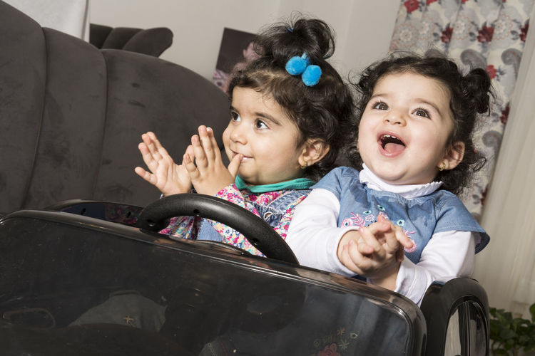 Happy little girls playing and enjoying with their toys present in living room