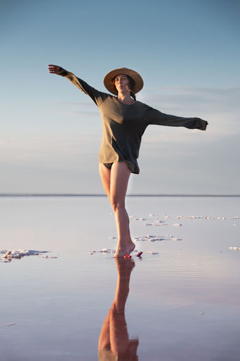 Evening view of the shallow salty pink lake. reflection. a young woman in a hat walks on the water 