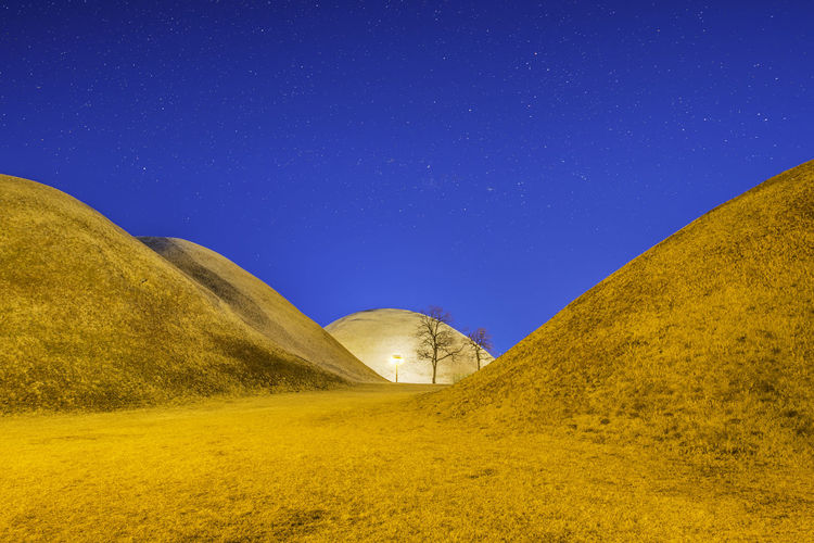 Scenic view of land against clear blue sky at night