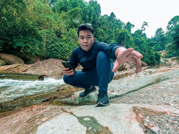 Portrait of young man using mobile phone on rock
