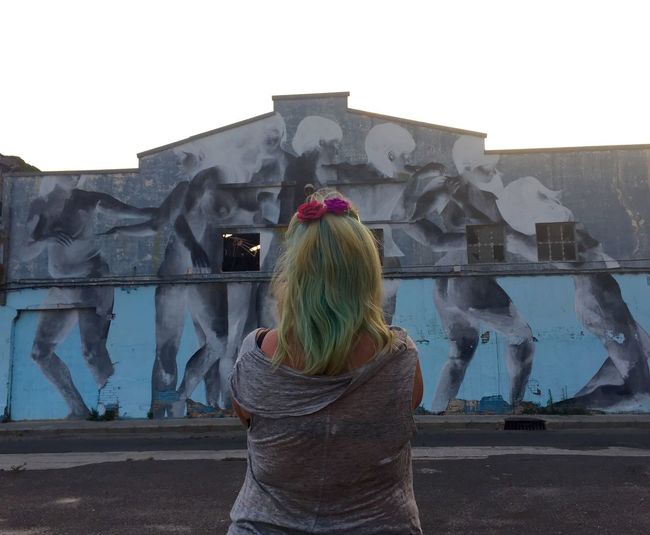 Rear view of woman standing against graffiti wall