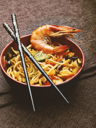Close-up of prawn and noodles in bowl with chopsticks