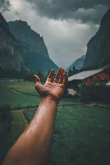 Close-up of human hand against mountain range