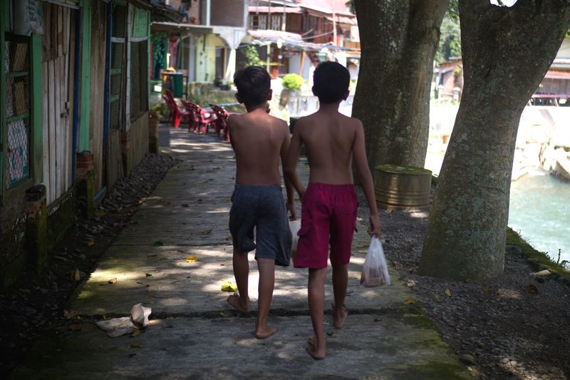 Two asian boys are walking together, they are getting ready to start swimming in the river again