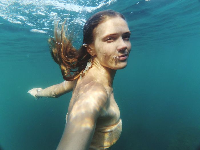 Side view portrait of woman swimming undersea