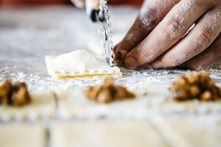 Cropped hands cutting ravioli dough