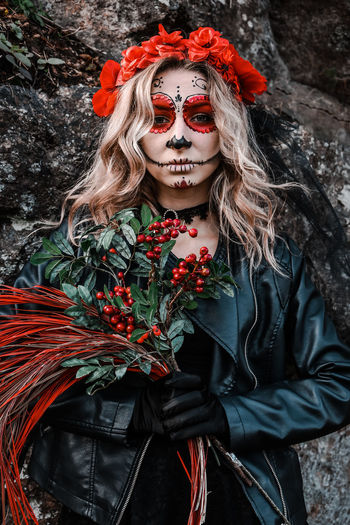Closeup portrait of calavera catrina. young woman with sugar skull makeup and red flowers. dia