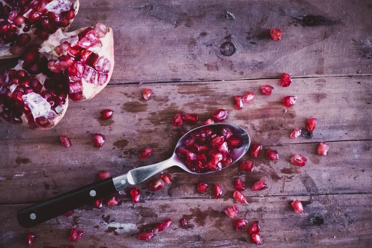 Close-up high angle view of pomegranate seeds with spoon on table