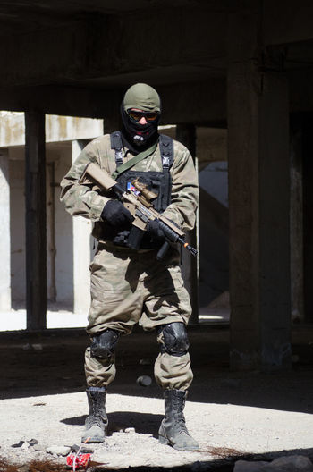 Soldier holding machine gun while standing in building